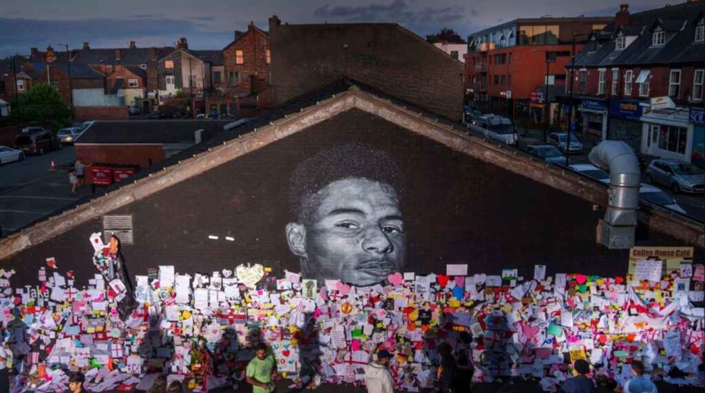 Tributes are placed in front of a huge mural of Marcus Rashford